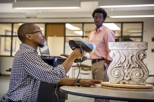 Art + Design CxC Studio Graduate Assistant Matty Williams, left, and CxC Studio Media Specialist and Peer Mentor O'mar Finley demonstrate the studio's new handheld 3D scanner to members of the local art and design community.Photo by Eddy Perez, LSU University Relations