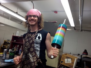 Male student with pink bandana holds rainbow roll