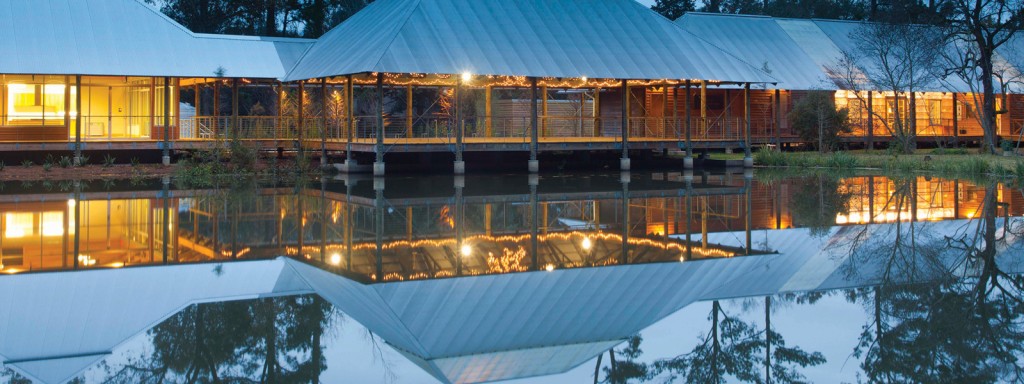 LSU Hilltop Arboretum at twilight, illuminated building reflected on pond water