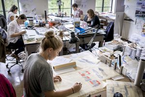 hth华体会体育app官网Blonde female student works at table in lsu architecture studios, other students in background