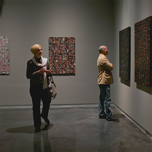 A man and woman observe art hanging in gallery