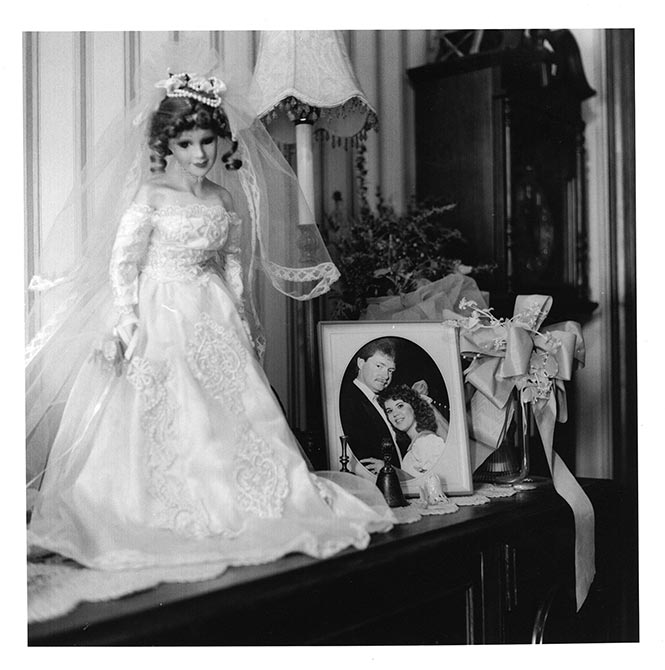 Doll in wedding dress next to framed wedding portrait, lsu intermediate photography