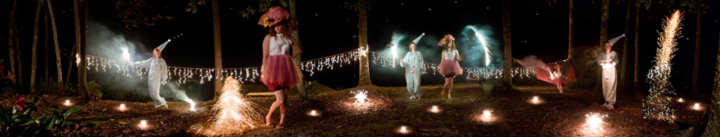 Panorama photo of people in costume, fire glowing in woods at night.LSU BFA Studio Art Photography