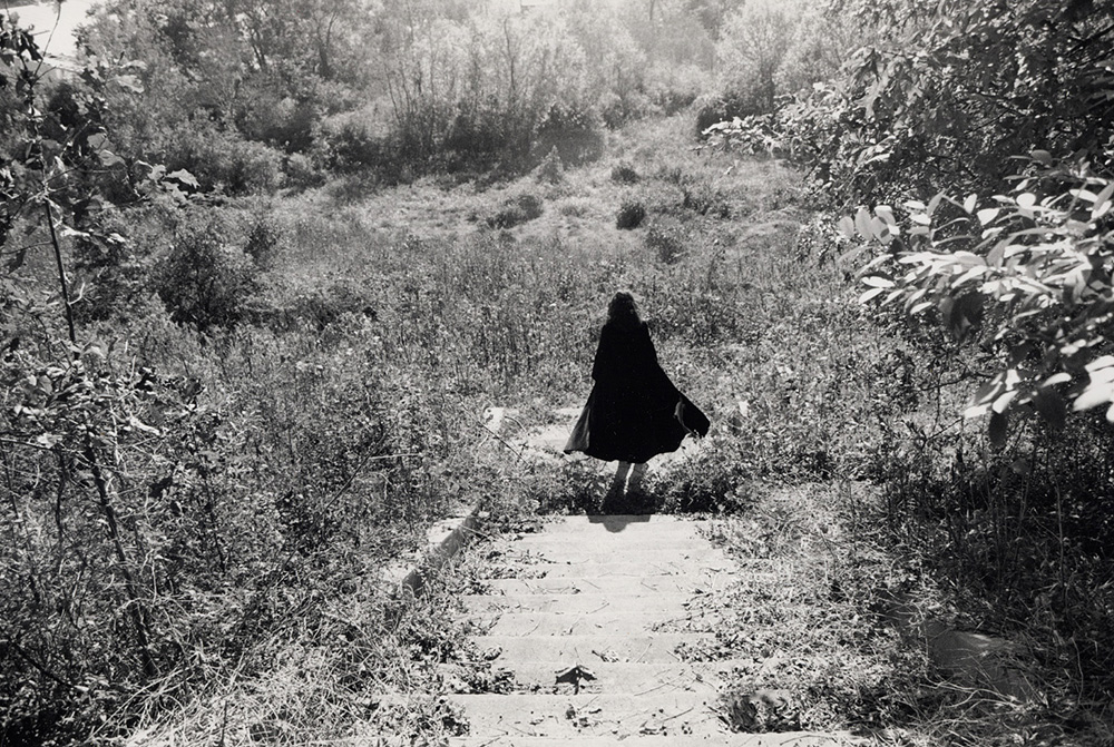 Woman in black coat in wild