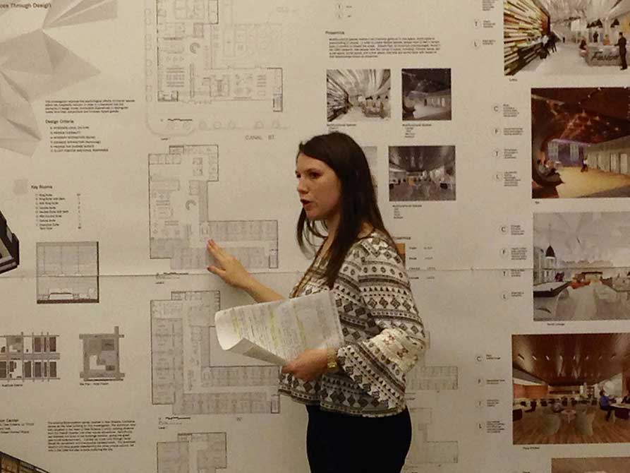 Girl points at floorplan on wall.lsu interior design student work