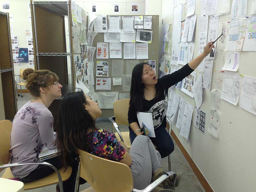 Young woman points at board.lsu interior design student work