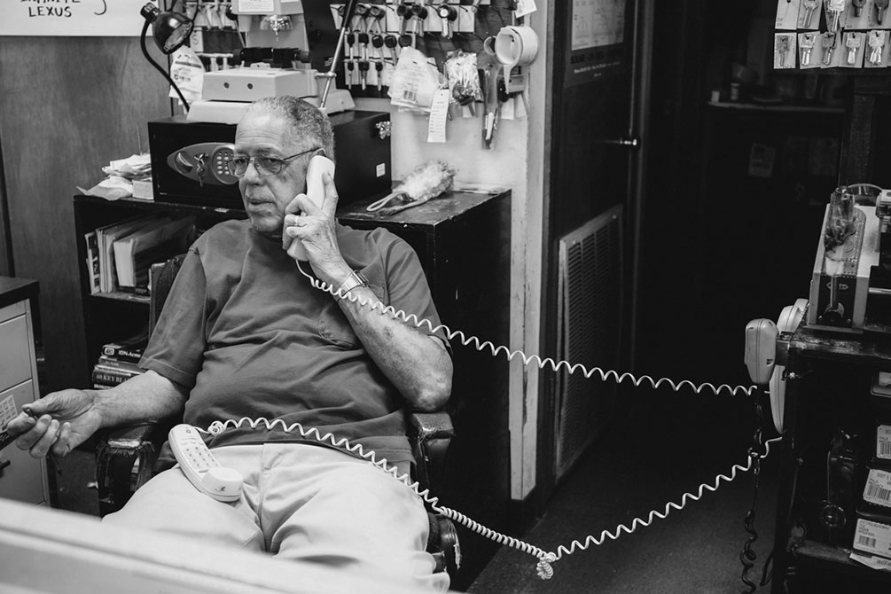 An old man talks on the telephone in his office