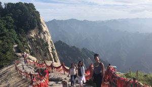 Three female students hike mountain trail in China