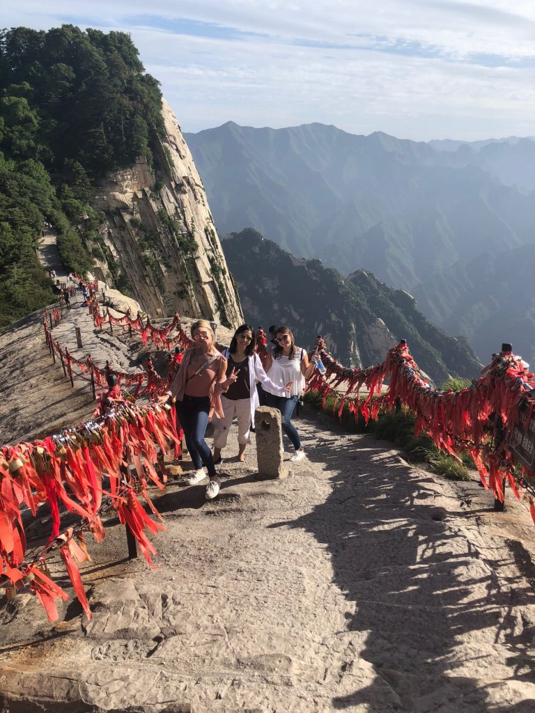 Students hiking to peak of chinese mountain on pathway with red fabric lining the fence