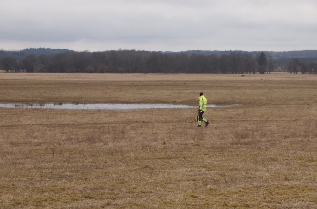 Man in high visibility jacket marks out distances on a site