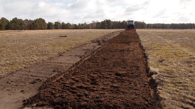 Tractor scrapes up dirt in a field