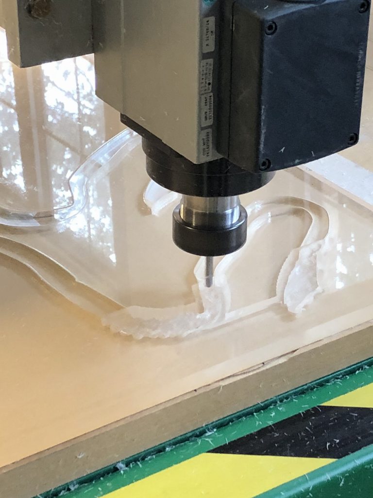 Computer controlled machine cutting a river shape design in clear material