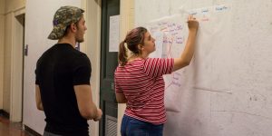 Female student draws on board, male student watches.