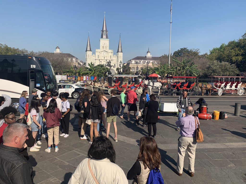 A group of people look toward white St Louis Cathedral.