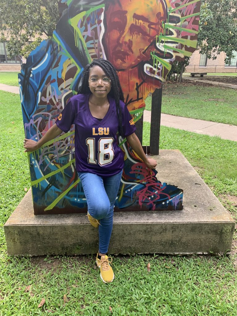 Female student in purple football jersey by colorful sculpture