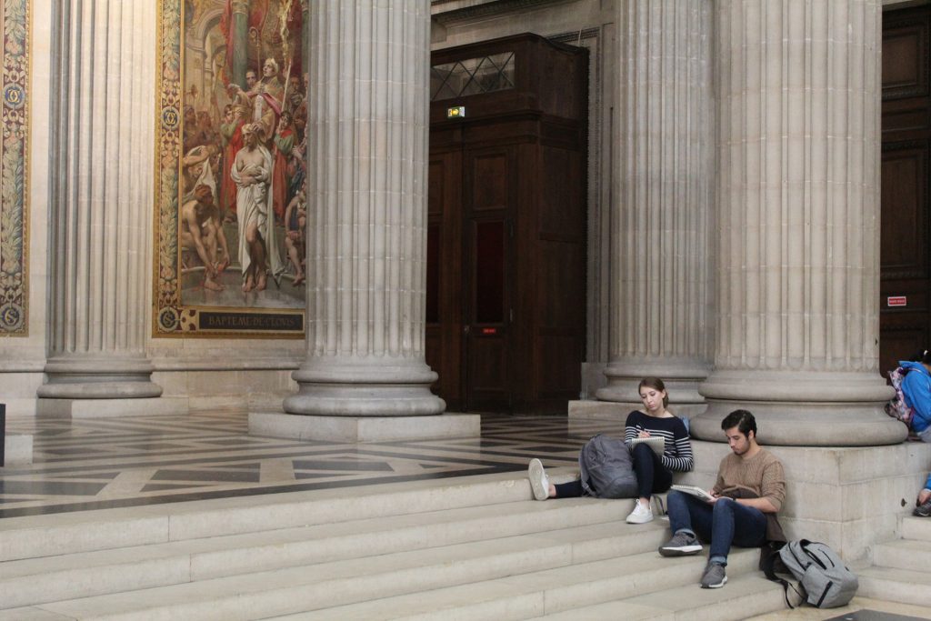 students sitting on steps by columns