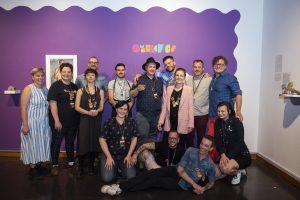 group in front of Queeramics exhibition sign