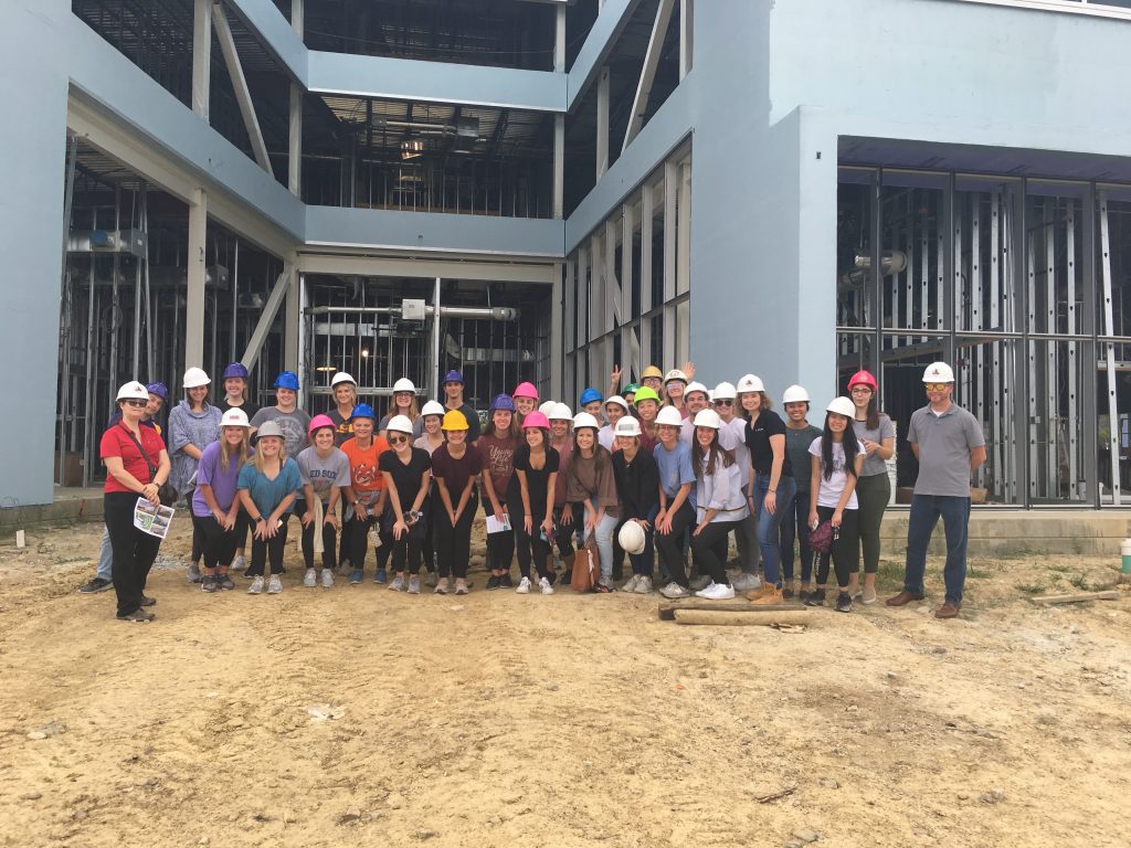 Students in hard hats by building