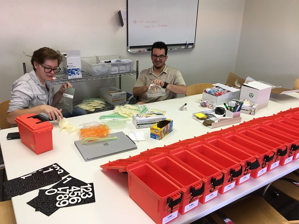 Male and female student sit at table with orange boxes