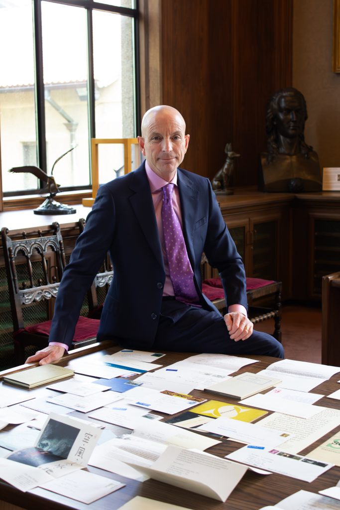 man in suit and purple tie by papers on table