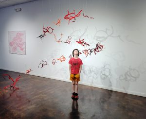 child standing in suspended hanging sculpture