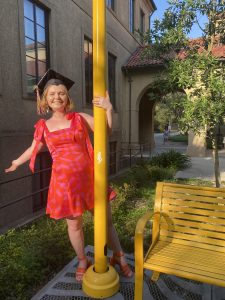 Meredyth Yorek with grad cap by yellow bench at LSU