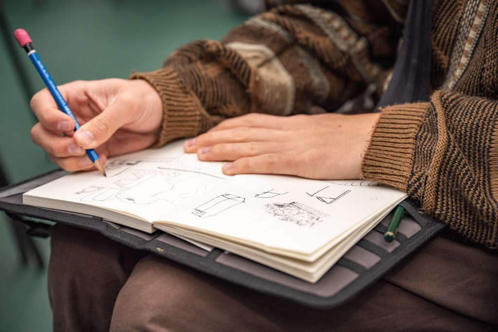 hands sketching designs in notebook