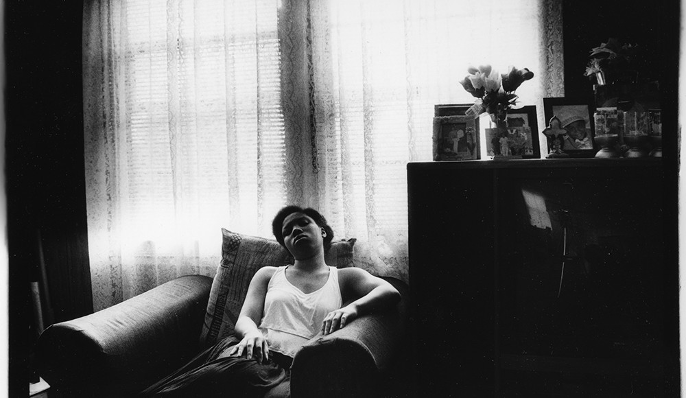 Young black woman in chair, black and white photo.